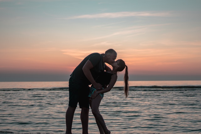 Muž so ženou na pláži, bozk, západ slnka, romantické